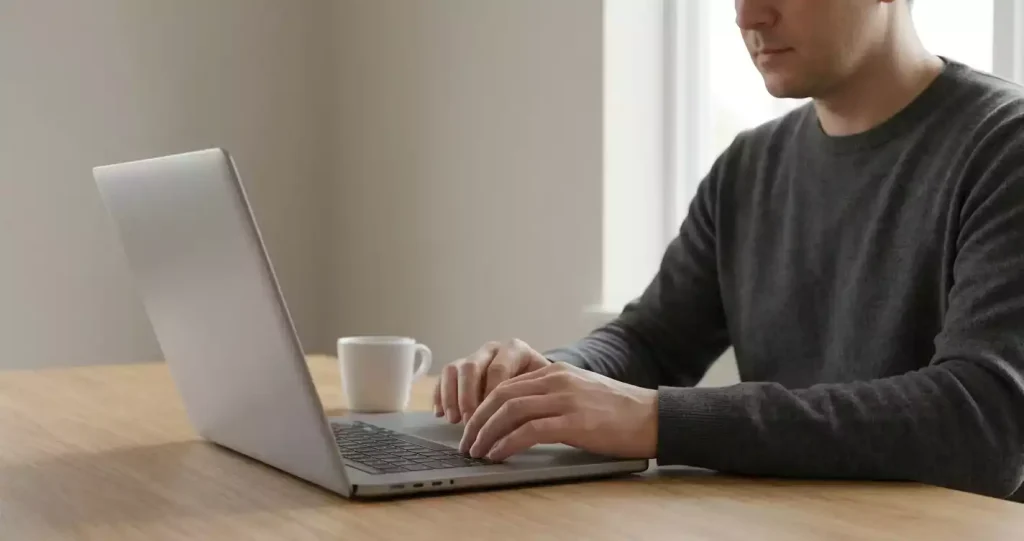Persoon achter laptop op een bureau die een website kritisch inspecteert
